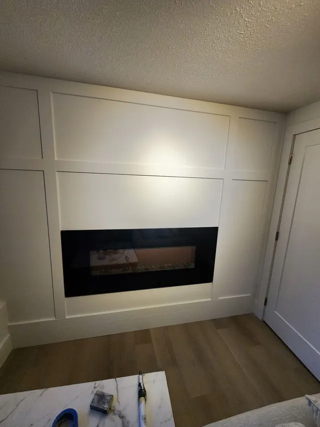 Finished basement renovation with electric fireplace feature wall by Valart Solutions